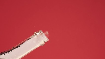 Slow motion of champagne cork exploding from bottle. Close-up of champagne or sparking coctail. On red background. - Powered by Adobe