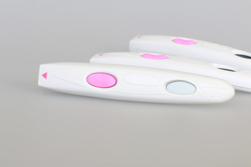 pregnancy test close-up with a big pink button on a gray background
