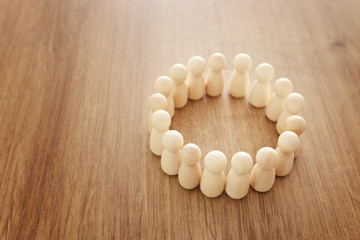 Business image of wooden figures forming a circle over wooden table. Concept of structure,...