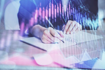 Forex graph on hand taking notes background. Concept of research. Multi exposure