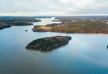 Aerial view of blue lake with island and green forests in Finland. Drone photography