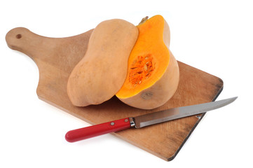 Butternut coupé en deux sur une planche à découper avec un couteau sur fond blanc