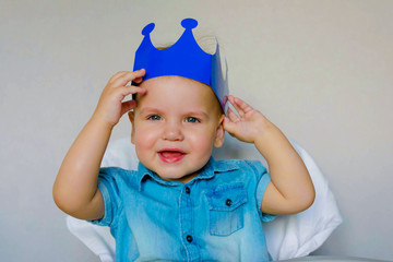 Little boy, Prince, baby king smiling sitting in a high chair. Funny knight Kid 1 year.