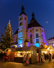 Weihnachtsmarkt in Regensburg am Abend mit beleuchteter  Neupfarrkirche  und Mond