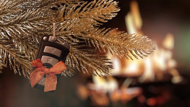 Christmas gift - car key. A golden christmas tree with car key against burning fireplace
