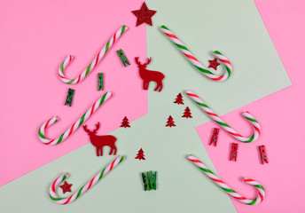 Christmas composition. Candy, red Christmas deers and decorations toys on pink and green background. Christmas, winter, new year concept. Flat lay, top view