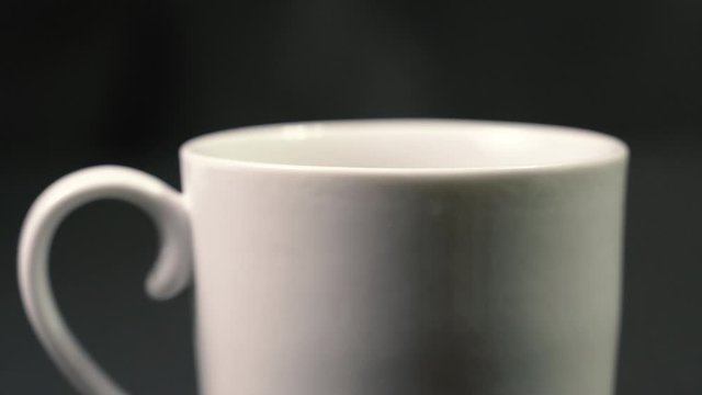Pouring coffee powder on  white cup on black background , ground coffee , making coffee Spoon Pouring freshly ground coffee on mug 