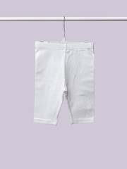 Baby-girl pants hanging on shoulders isolated on lilac background for spring and autumn wardrobe/ Baby clothes