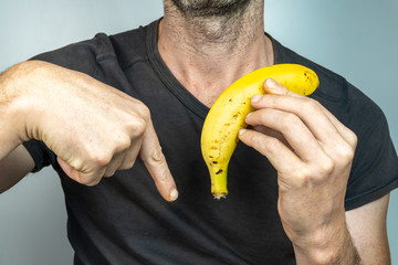 caucasian White man with a banana in his hand and pointing down, isolated on White background
