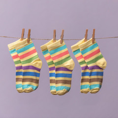 Set of colorful children's socks hanging on the clothesline  on a lilac background