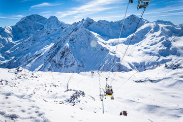Winter panoramic view of the snowy high mountains of Elbrus and cableway with funicular in the Russia