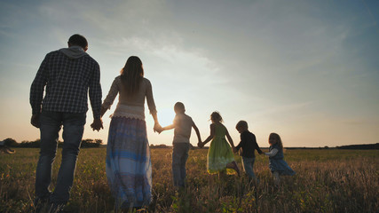 A large family of six people walk on the floor at sunset.