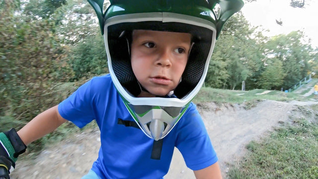 A young boy enjoys a ride on BMX track..Close-up of helmet and rider's face.