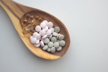 Supplements for vegans displayed on a wooden spoon: iron, vitamin B 12 and vitamin D. 