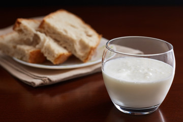 glass cup with kefir on a dark table and background. Handmade bread in the background