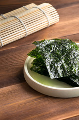 Crispy Nori Sheets and bamboo mat on wood table. Verical photo. 