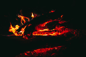 Fire on wooden or firewood at night on the dark or black light background.