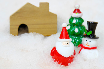 Santa Claus and Snowman and Christmas Tree and Wooden House on White Snow