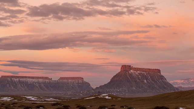 Timelapse of colorful sunrise over Factory Butte in the Utah desert as clouds move through the sky.