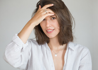 Fototapeta premium Portrait of a young successful woman with dark hair. The woman straightens her hair with her hands.