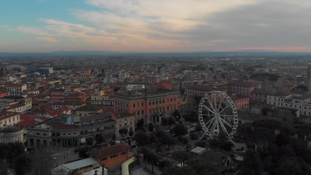 Drone pan on italian city at sunset with panoramic wheel
