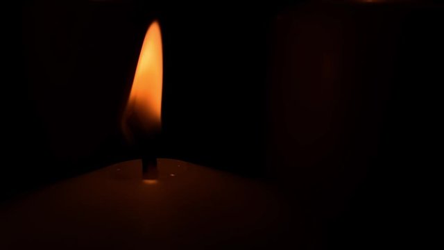 Close-up Single Orange flame on black background, slow fire movement of a burning candle, static image of flame on black background, slow motion