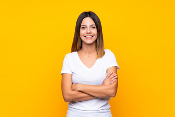 Young woman over isolated yellow background keeping the arms crossed in frontal position