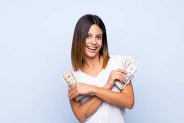 Young woman over isolated blue background taking a lot of money