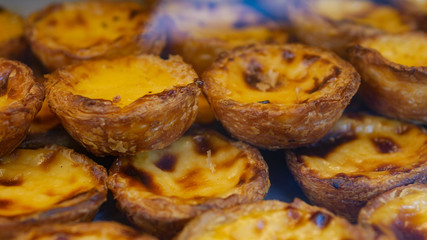 Freshly baked Pastel de Nata by a window, with golden layers, creamy vanilla filling, and a touch of cinnamon. The warm light enhances its crisp texture, capturing the essence of Portuguese pastry.