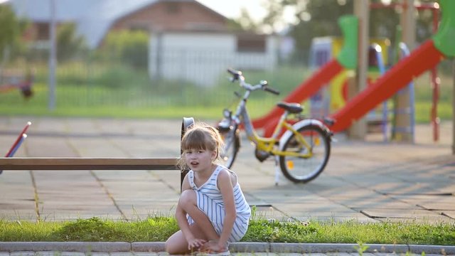 Little Child Girl Jumping Happily And Then Painfully Trips Over And Twists Her Ankle Bone.