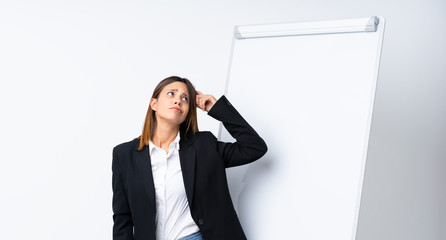 Young woman giving a presentation on white board having doubts and with confuse face expression