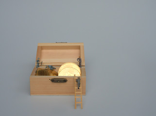 Miniature people as worker are working on the Bitcoin Crypto currency that is stored in the wooden box.