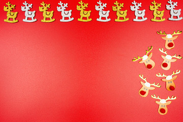 Naklejka premium Background made of gold and silver reindeer and reindeer faces on the right, isolated on a red background.