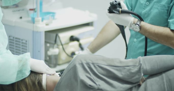 Female patient lying on bed during gastrologist performing endoscopy examination in the office room.