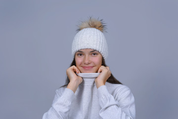 studio portrait of young beautiful woman covering face with woolen sweater