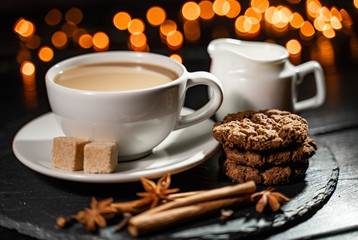 A cup of coffee against the backdrop of the Christmas background. Cookies, spices.