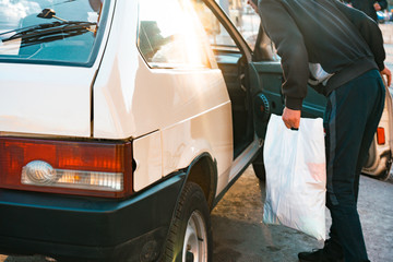 A man with white plastic bag speaking with driver through the open passenger's door. Car. Conversation. Taxi. Ride