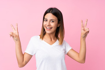 Young woman over isolated pink background showing victory sign with both hands