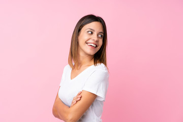 Fototapeta premium Young woman over isolated pink background with arms crossed and happy