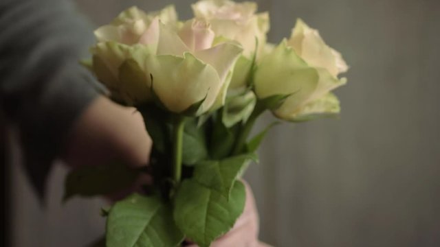 Hand placing bunch of pink and white pastel roses in a vase