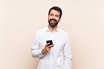 Young man with beard holding a mobile laughing