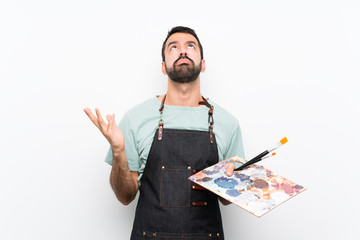 Young artist man holding a palette over isolated background frustrated by a bad situation