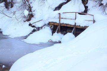 Frozen pond with a wooden bridge in winter in a park at the ski resort of elbrus in the kabardino-balkar republic