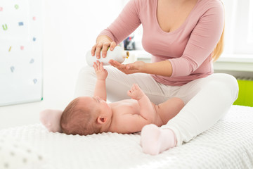 Baby massage background. Kids therapist applying massage oil to baby boy. Mother massaging her...