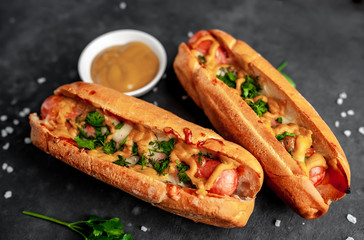 french hot dogs baked with cheese and mustard on a stone background