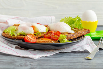 Appetizing snack of sandwiches with poached egg and vegetables
