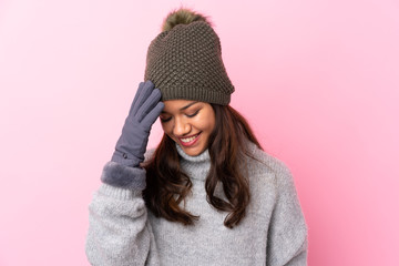 Young Colombian girl with winter hat over isolated pink wall laughing