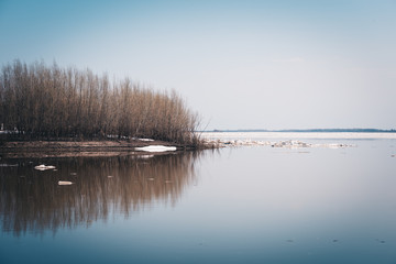 Early spring drift on beautiful river with broken off pieces of ice float down the stream.