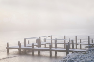 Fishing pier jetty in winter fog and mist