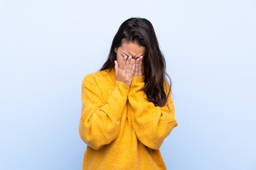 Young Colombian girl with sweater over isolated blue background with tired and sick expression